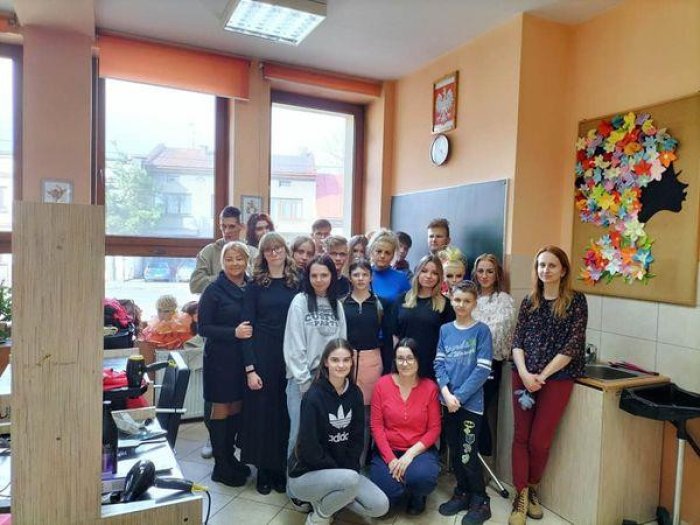 Uczniowie technikum fryzjerskiego i opiekunowie pozują do zdjęcia z wychowankami internatu.