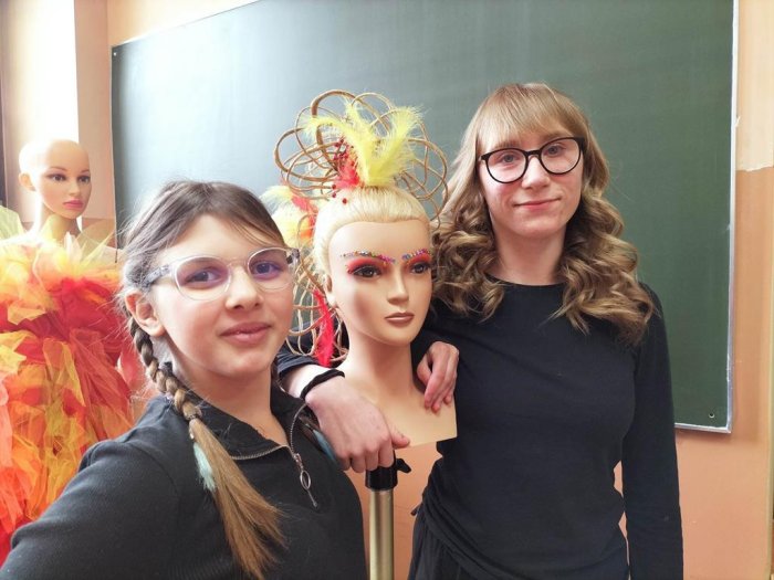 Wychowanki internatu pozują do zdjęcia  manekinem z kolorową fryzurą.