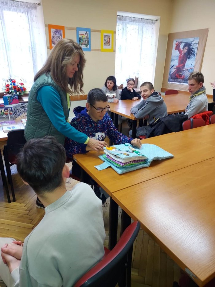 Pani bibliotekarka prezentuje uczniom książki przestrzenne. 